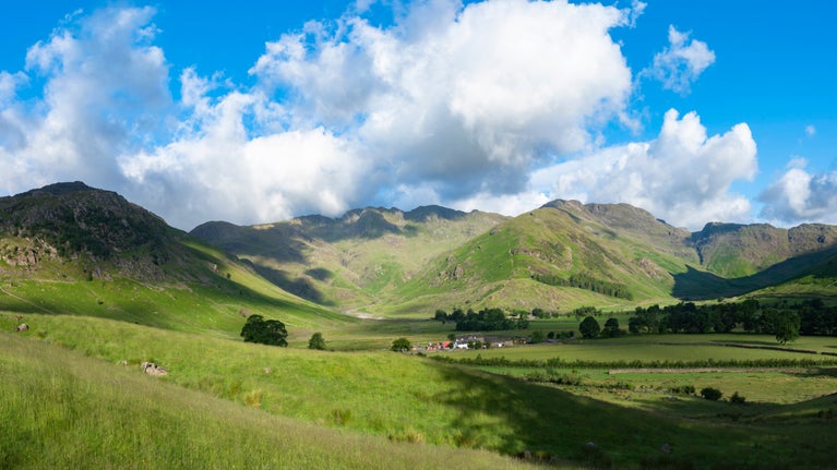 View of The Langdale Pikes showing hills and blue skies and white clouds seen from Great Langdale Campsite, Cumbria